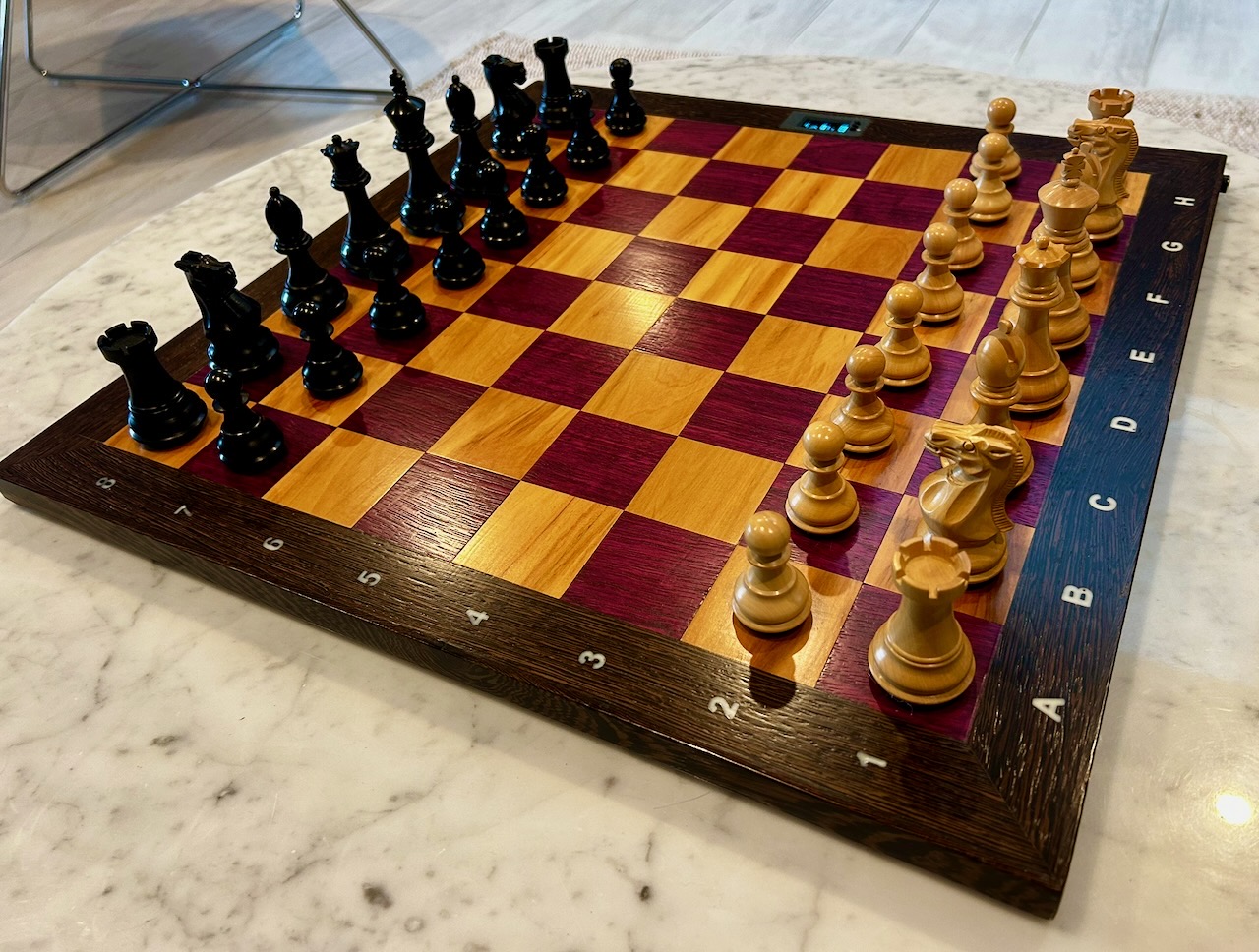 The hardwood squares and dark frame of the board, seen at a low angle